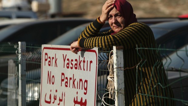 A Syrian woman waits for other family members to cross into Turkey as the evacuation of fighters and civilians from the last remaining opposition stronghold in Aleppo resumed after days of delays.