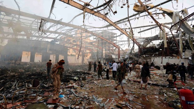 People inspect the aftermath of an air strike in the Yemeni capital, Sanaa, which killed at least 100 people and injured hundreds more.
