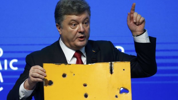 Ukrainian President Petro Poroshenko holds a fragment of a bus he says shows a Russian rocket attack while addressing the World Economic Forum in Davos.