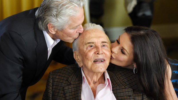 Actor Kirk Douglas, centre, gets a kiss from his son Michael Douglas, left, and Michael's wife Catherine Zeta-Jones during his 100th birthday party.