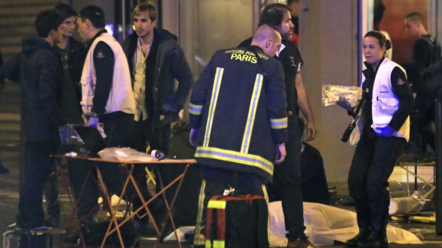 Rescue workers at the scene as victims lay on the pavement outside a Paris restaurant on Friday.