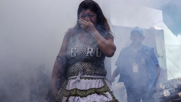 A woman covers her mouth while city workers fumigate insecticide to help combat the Aedes Aegypti mosquitoes that transmit the Zika virus, at the San Judas Community in San Salvador, El Salvador, last week.