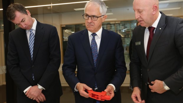 Justice Minister Michael Keenan, Prime Minister Malcolm Turnbull and AFP acting national manager of specialist operations Simon Walsh as Mr Turnbull examines a 3D printed gun.