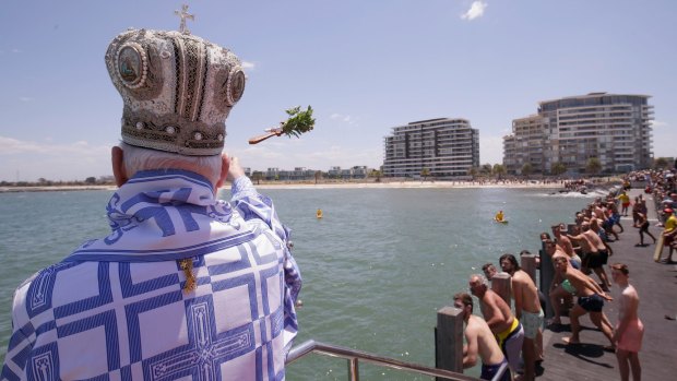His Grace Bishop Ezekiel of Dervis throws the cross into the water during The Blessing of the Waters at Princes Pier in Port Melbourne.