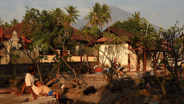 A man and his child looking towards Mount Agung in Purwakerti, in a safe zone
