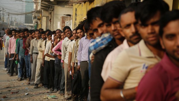 Indians stand in a queue to deposit and exchange discontinued currency notes outside a bank in New Delhi, India.