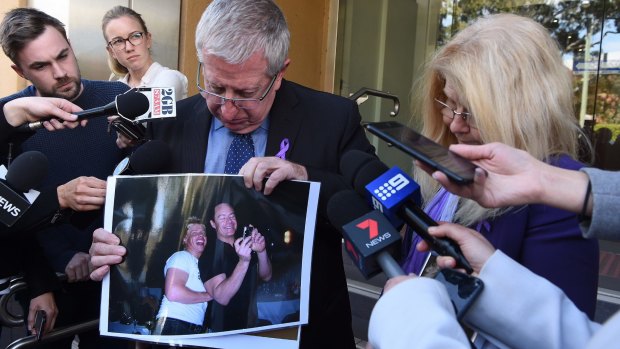 Mark and Faye Leveson show a photo of their son Matthew Leveson with his partner Michael Atkins outside the Coroner's Court on Friday.