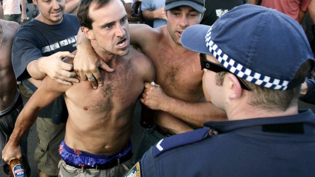 A man confronts police, holding a beer bottle during the Cronulla riots.