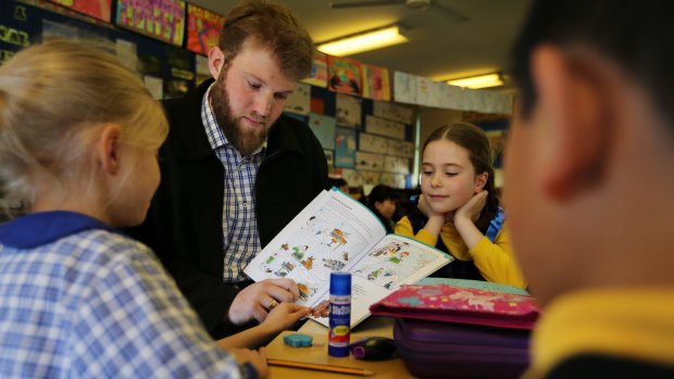 Michael Hanaghan shows a Latin textbook to Haberfield Public School students (from left) Elke Chapin, Mila Ossowaka and Jazz Lee.