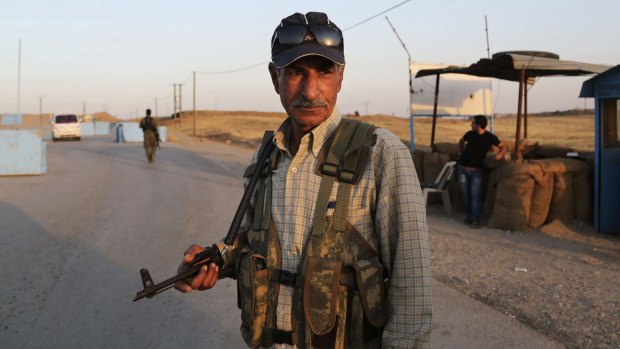 Syrian Kurdish Peshmerga fighters stand guard at a refugee camp in Derike, Syria. 