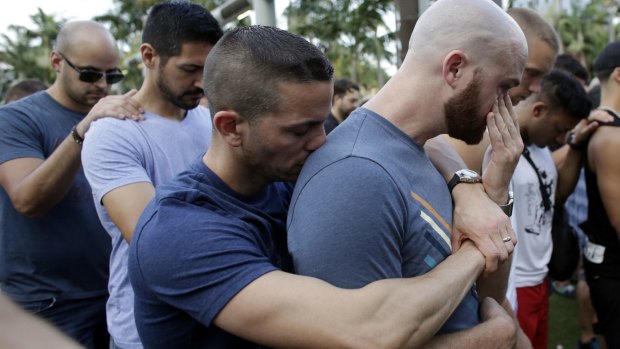 Caleb McGrew, 36, right, wipes tears as he stands with his partner Yosniel Delgado Giniebra, 37, centre, during a vigil in memory of the victims of the Orlando mass shooting, 
