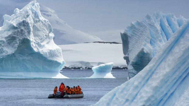 A small boat explores sculpted icebergs near Cuverville Island, Antarctica.