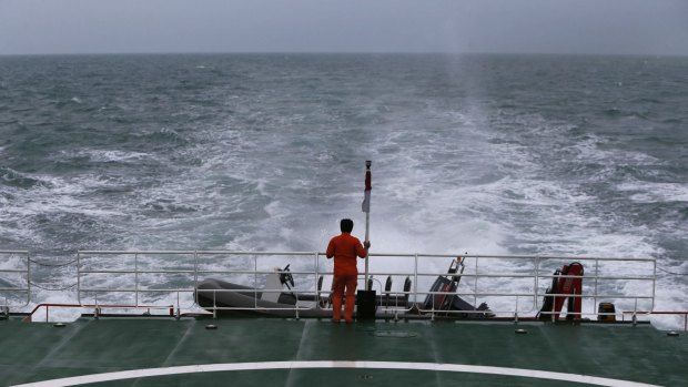 A rescue member stands on the deck of SAR ship KN Purworejo during a search operation for passengers onboard AirAsia flight QZ8501, in the Java Sea.