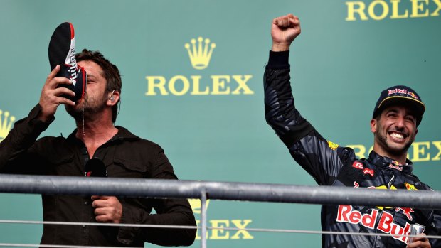Actor Gerard Butler does a shoey on the podium with Daniel Ricciardo.