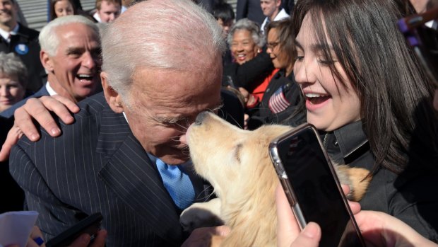 Former Vice President Joe Biden gets a kiss from a dog as he greets the crowd on Capitol Hill in Washington, Wednesday, March 22, 2017, following an event marking seven years since former President Barack Obama signed the Affordable Care Act into law. 