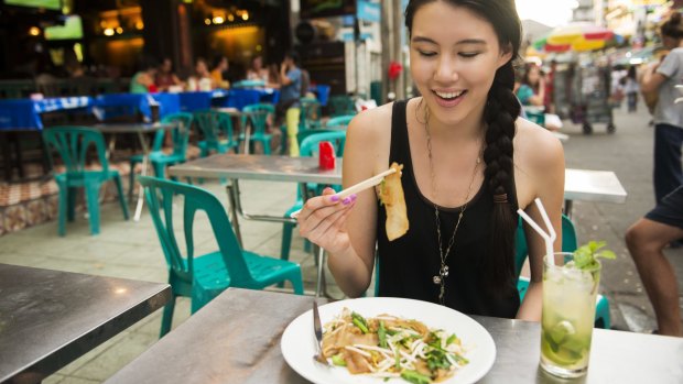 A solo female traveler enjoys a meal in Bangkok.