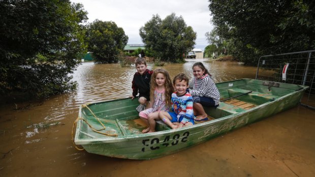 Jake Baker, Ivy Baker, Logan Farrar and Layla Baker use a boat to get from their front door on Simmie Road, Echuca.