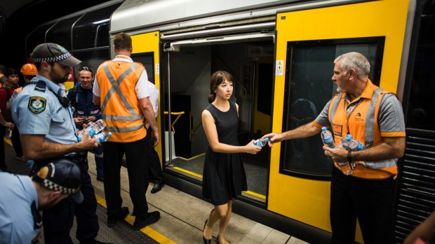 A woman is given water after being trapped on a train near Wynyard Station.