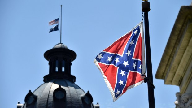 The South Carolina and American flags fly at half-staff behind the Confederate flag erected in front of the State Congress building in Columbia, South Carolina.