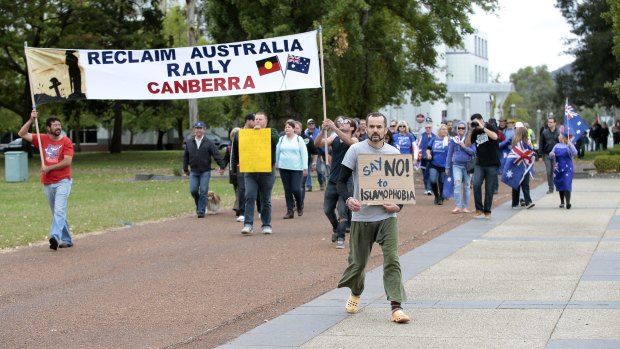 Protester Ben Keaney, centre, marches against supporters of Reclaim Australia in front of the National Library of Australia on Saturday.