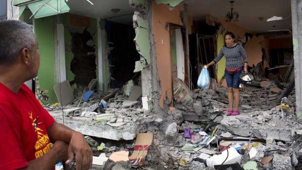 Karina Vera leaves her brother's house after recovering a cooking pot and other usable items one week after the devastating earthquake on the outskirts of Pedernales, Ecuador.