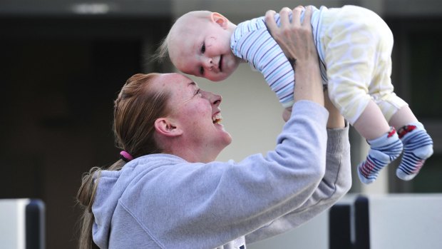 Canberra Caps player Michelle Cosier picks her son up Levi Cosier, 7 months, after training on Tuesday. 