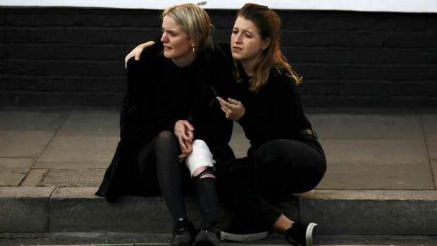 An injured woman is comforted outside the Parsons Green tube station in London after the explosion.