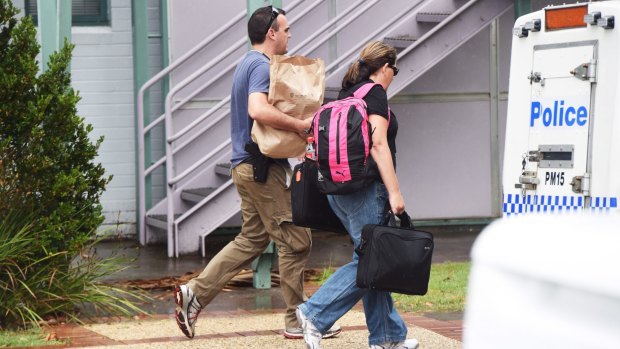 Detectives leave Port Macquarie police station with bags of evidence.