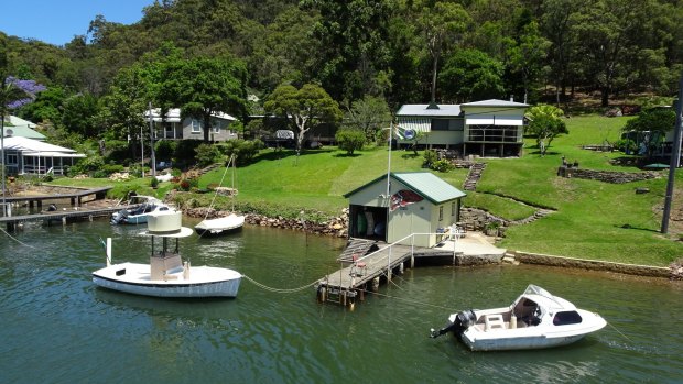 The flooded river valley is surrounded by thick green bushland, mangroves and sandstone cliffs.