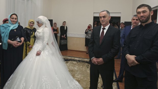 A bride, Chechen Kheda Goilabiyeva, and Chechen police officer Nazhud Guchigov stand in a wedding registry office.
