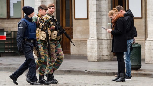 Belgian soldiers and a police officer patrol in the centre of Brussels. The city's predominantly Muslim suburb of Molenbeek was the home of a suspected ringleader of the November 13 Paris attacks.