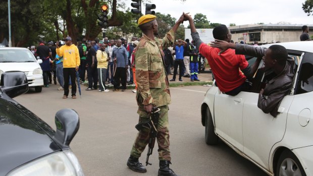 A man holds the hand of a soldier as euphoric crowds march on the streets of Harare, demanding the departure of President Robert Mugabe.