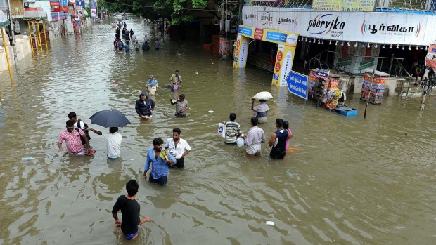 People wade through a flooded street in Chennai, in the southern Indian state of Tamil Nadu. 