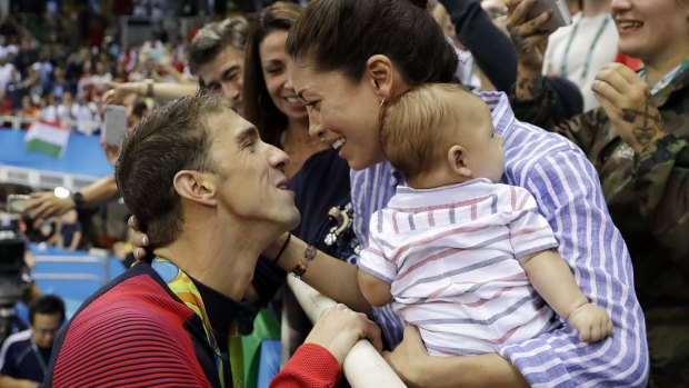 Michael Phelps celebrates a gold medal with fiance Nicole Johnson and baby Boomer.