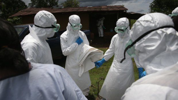  A burial team from the Liberian Red Cross prays before collecting the body of an Ebola victim from his home in Liberia.
