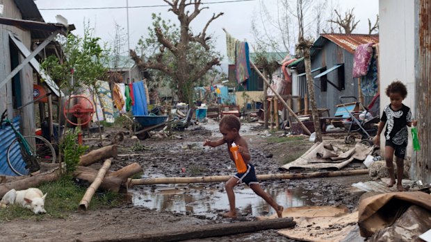 Young children walk through debris in Vanuata after Cyclone Pam hit in 2015.