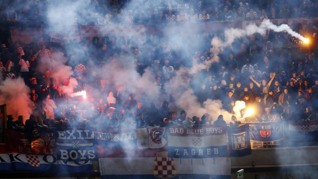 Croatian supporters throw flares into the pitch.