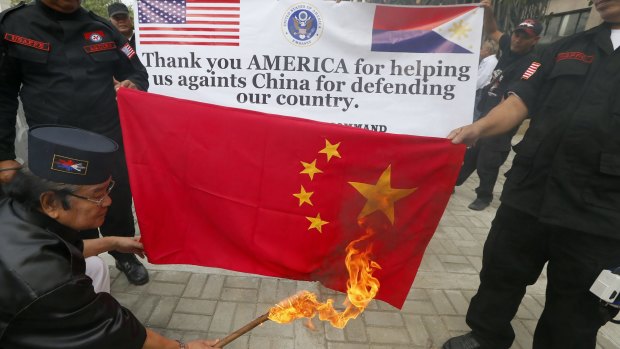 Protest leader Elly Pamatong burns a Chinese flag near the US embassy in Manila on Monday. 