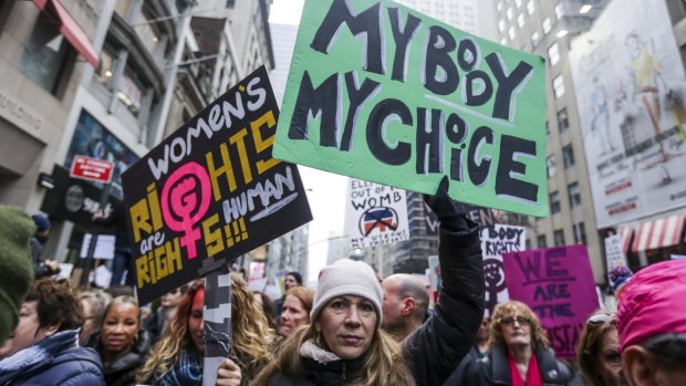 Demonstrators hold signs while marching towards Trump Tower during the Women's March in New York.