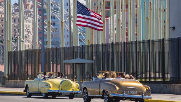 Tourists ride vintage American convertibles as they pass by the United States embassy in Havana.