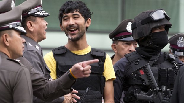 Police officers with a suspect in the Bangkok bombing, Yusufu Mieraili, on September 9.
