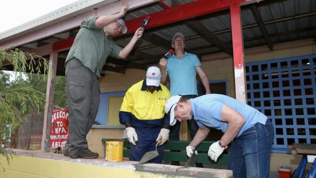 Prime Minister Tony Abbott and Social Services Minister Scott Morrison assist in the community hall upgrade in the Injinoo community.
