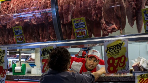 A butcher serves a customer at a market in Sao Paulo on Monday. 