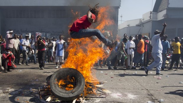 A protester jumps over a burning barricade in the capital.