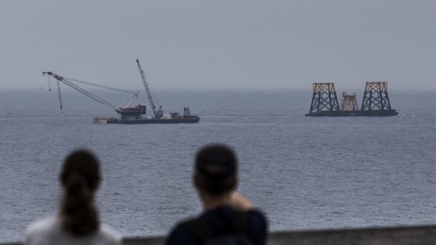 People look out at an offshore wind farm under construction off the coast of Rhode Island.