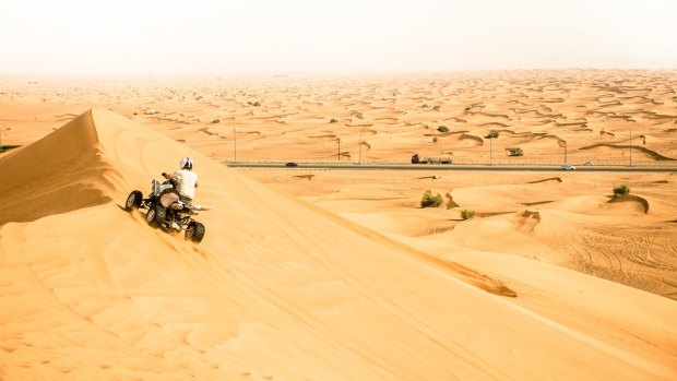 Riding across the dunes on a quad bike, Hatta, Oman.