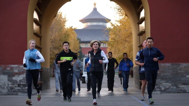 Foreign Affairs Minister Julie Bishop jogs with her security entourage at the Temple of Heaven in Beijing on Monday. 