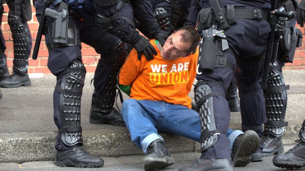 Riot police restrain a protester.