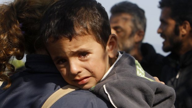 A boy cries on his mother's shoulder as they enter Macedonia from Greece.