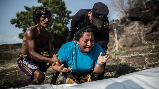 A woman mourns over the body of her brother, found in a clandestine grave, in a rural area of El Salvador. 